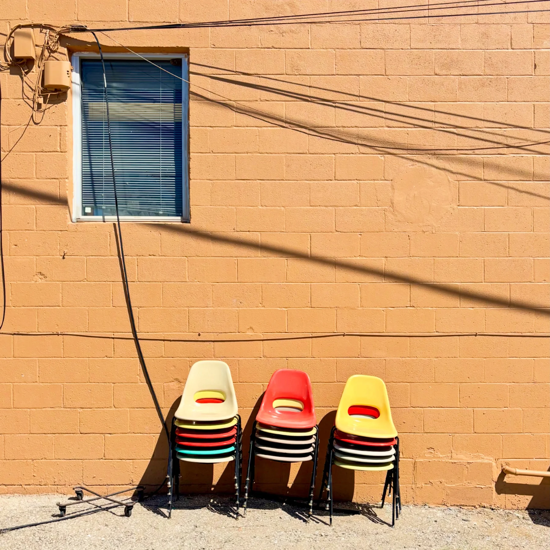 Colorful chairs against a yellow wall.