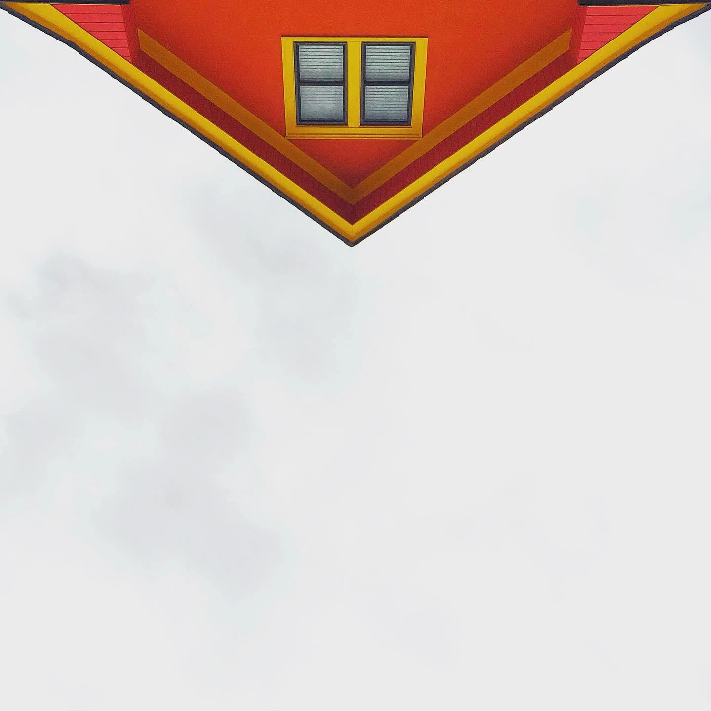 A red and yellow roofline pointing into a pale sky.